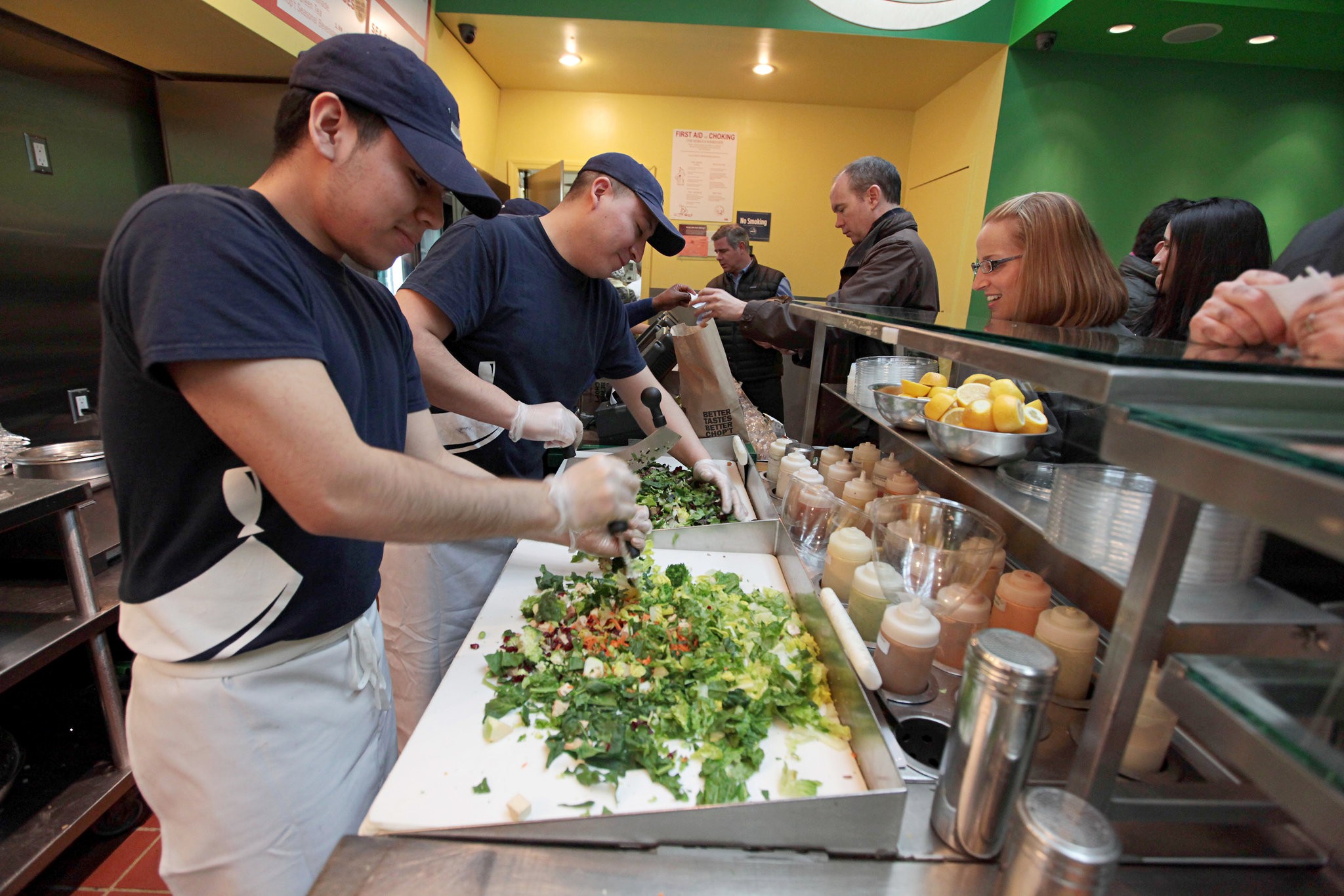 Choppers make salads on an assembly line in front of customers