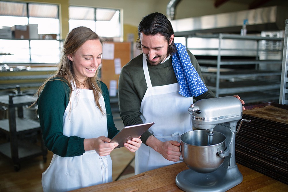 Paige and Ray use an iPad with the Great Harvest Bread Company LMS as they work through the Kitchen Aid training.