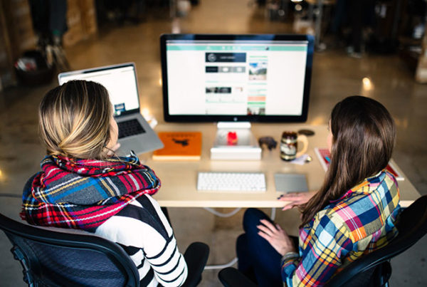 two women sitting at desk discussing lms project