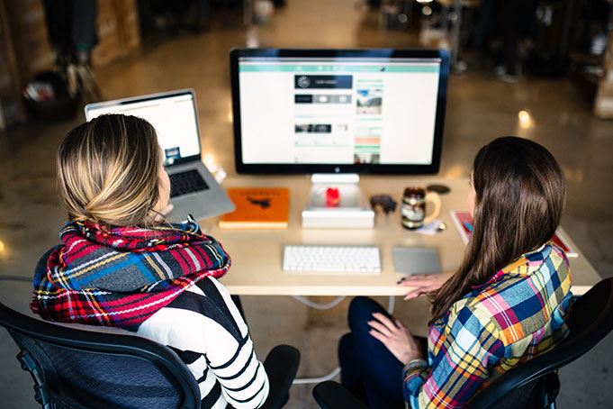 two women sitting at desk discussing lms project