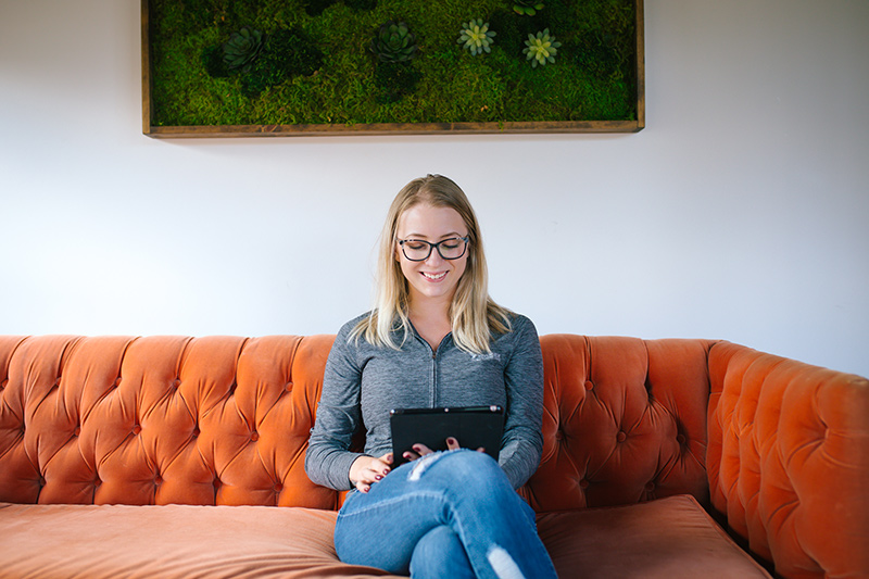 Wisetail LMS employee Cody Kirby sits in the Wisetail office on her iPad.