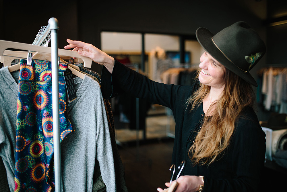 A retail employee hanging clothes on a clothing rack.