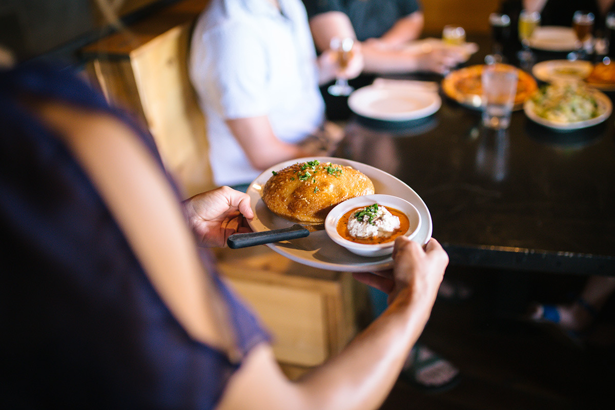 A waitress delivers a calzone to a table at a restaurant.