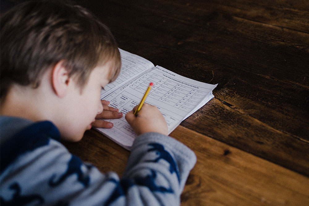 A young boy works on homework while at home.