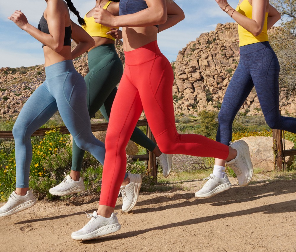 Wisetail LMS client Outdoor Voices models run on a trail in vibrantly colored leggings.