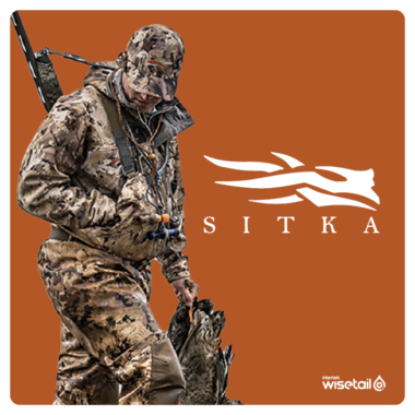 man wearing camouflage outfit with a gun on his back and holding a dead duck next to Sitka logo on rust background