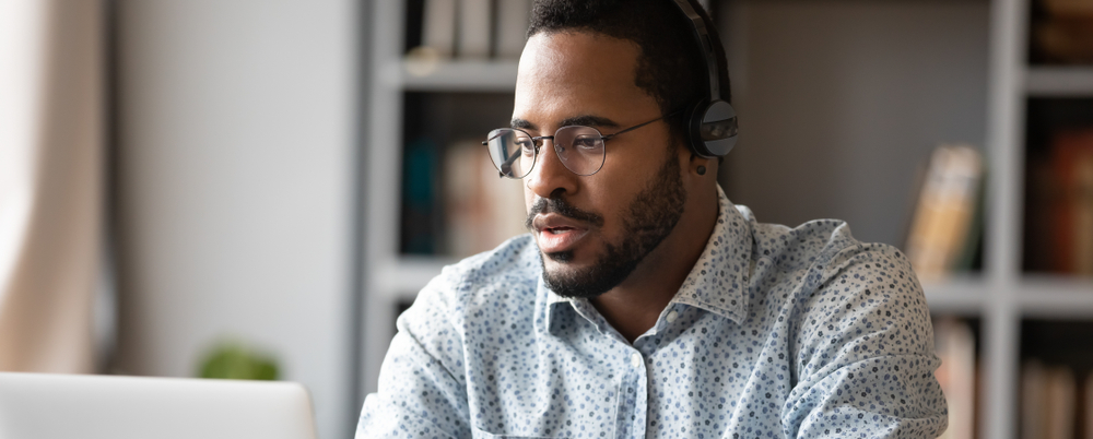 Photo: A focused young businessman studies an online course on his laptop.