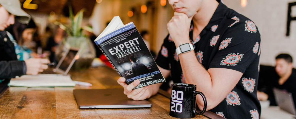 Photo: A young man reads a book on business secrets while sitting in a coffee shop.