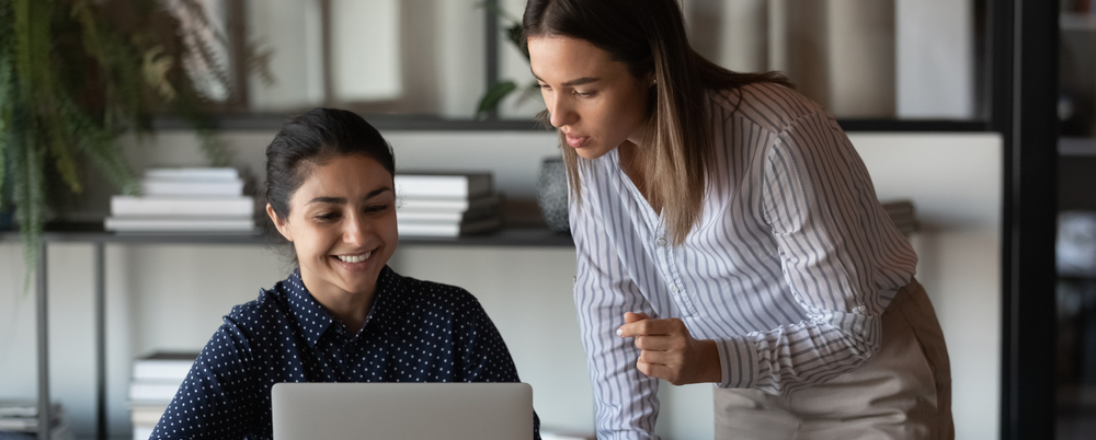 Photo: Female coworkers discuss a project at a laptop.