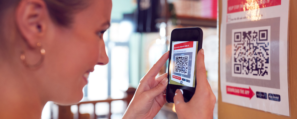 Woman With Mobile Phone Checking Into Venue Scanning QR Code During Health Pandemic
