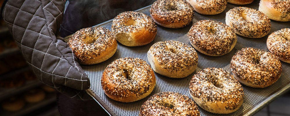 Fresh bagels being taken from the oven