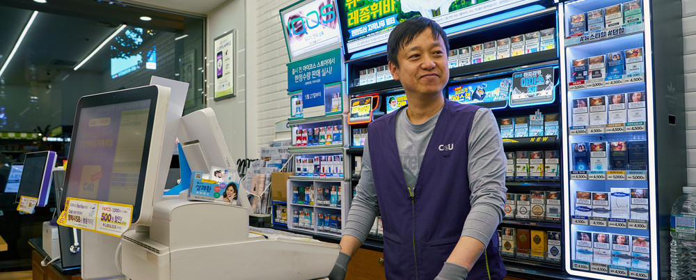 Convenience store employee standing behind cash register