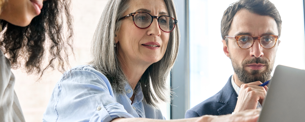 Coworkers examining a computer screen as a team